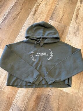 Schitt’s Creek Olive Green Cropped Hoodie with "Surviving Not Thriving" Print